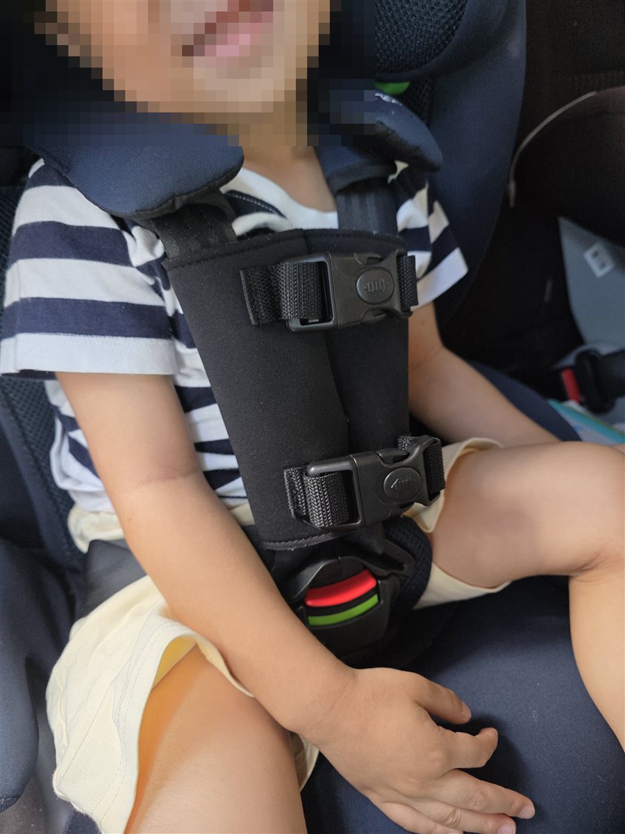 チャイルドシートに胸の高さで装着した抜け出し防止ベルト。子どもの顔部分にはモザイク加工済み