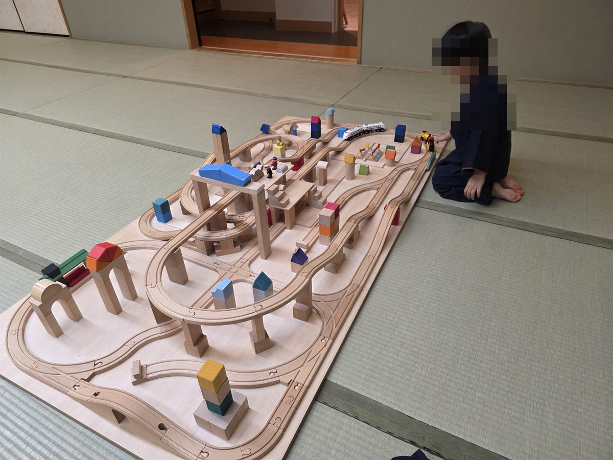 トレインルームで木製の線路と電車で遊ぶ様子。子どもの顔部分にはモザイク加工済み